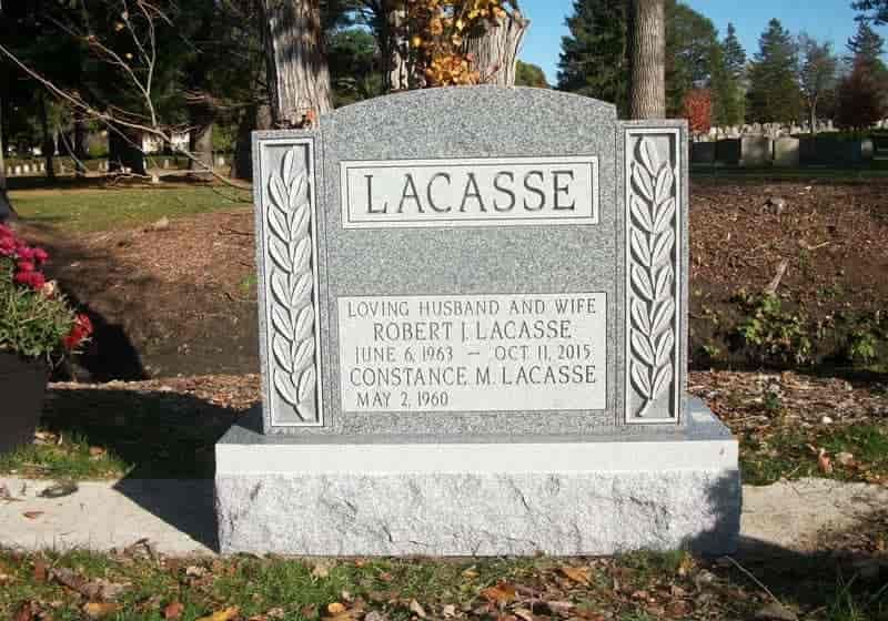 Gray granite headstone in a cemetery. The name LACASSE is at the top. Details include dates of birth and death.