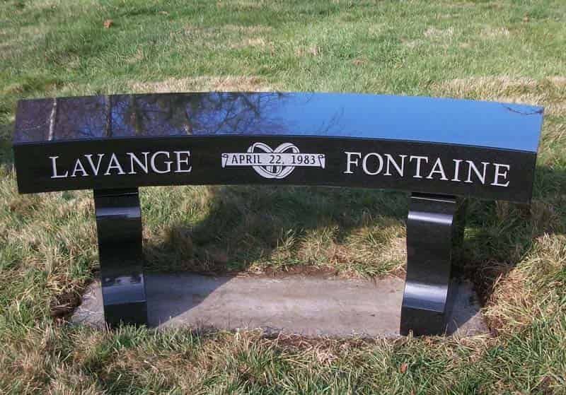 Black granite bench with the name Lavange Fontaine and a heart symbol on a grassy area.
