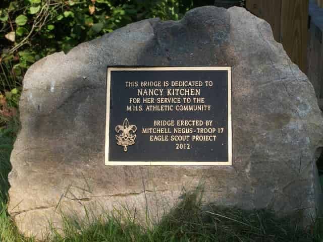 Plaque on a rock dedicated to Nancy Kitchen for her service to the MILS athletic community. Erected by Mitchell Megus-Troop 17 in 2013.