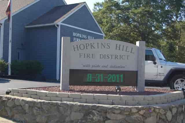 Hopkins Hill Fire District sign with digital date display, building in background, and Jeep.