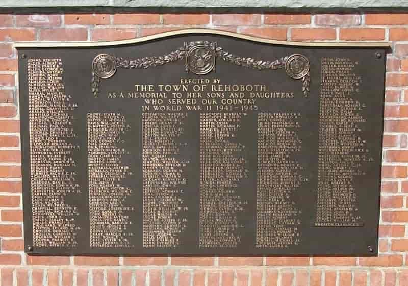 Bronze war memorial plaque on a brick wall. Lists names of those who served in World War II.