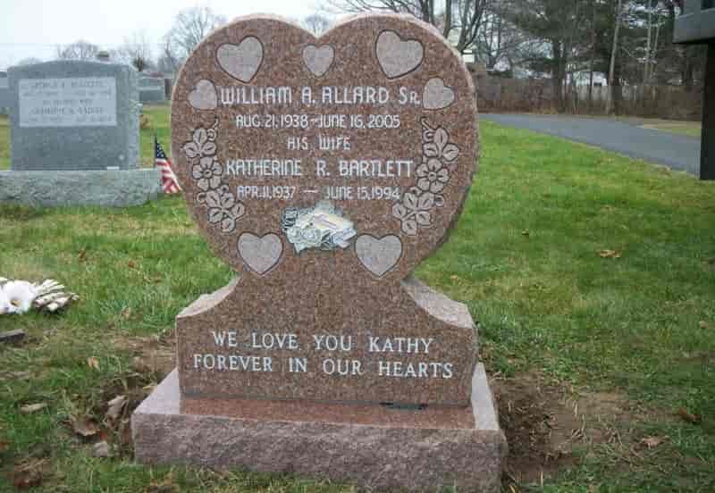 Heart-shaped tombstone with names William Allard & Katherine Bartlett, in a grassy cemetery. 