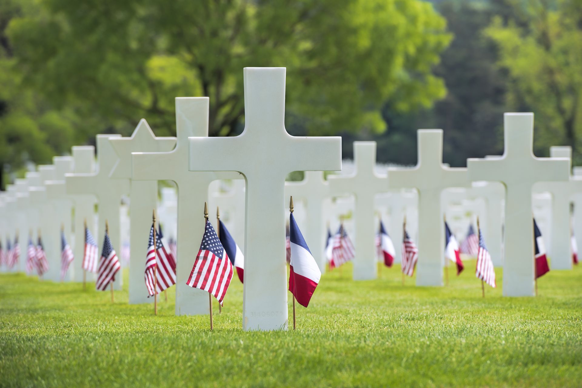 White crosses and flags in a cemetery on a sunny day.