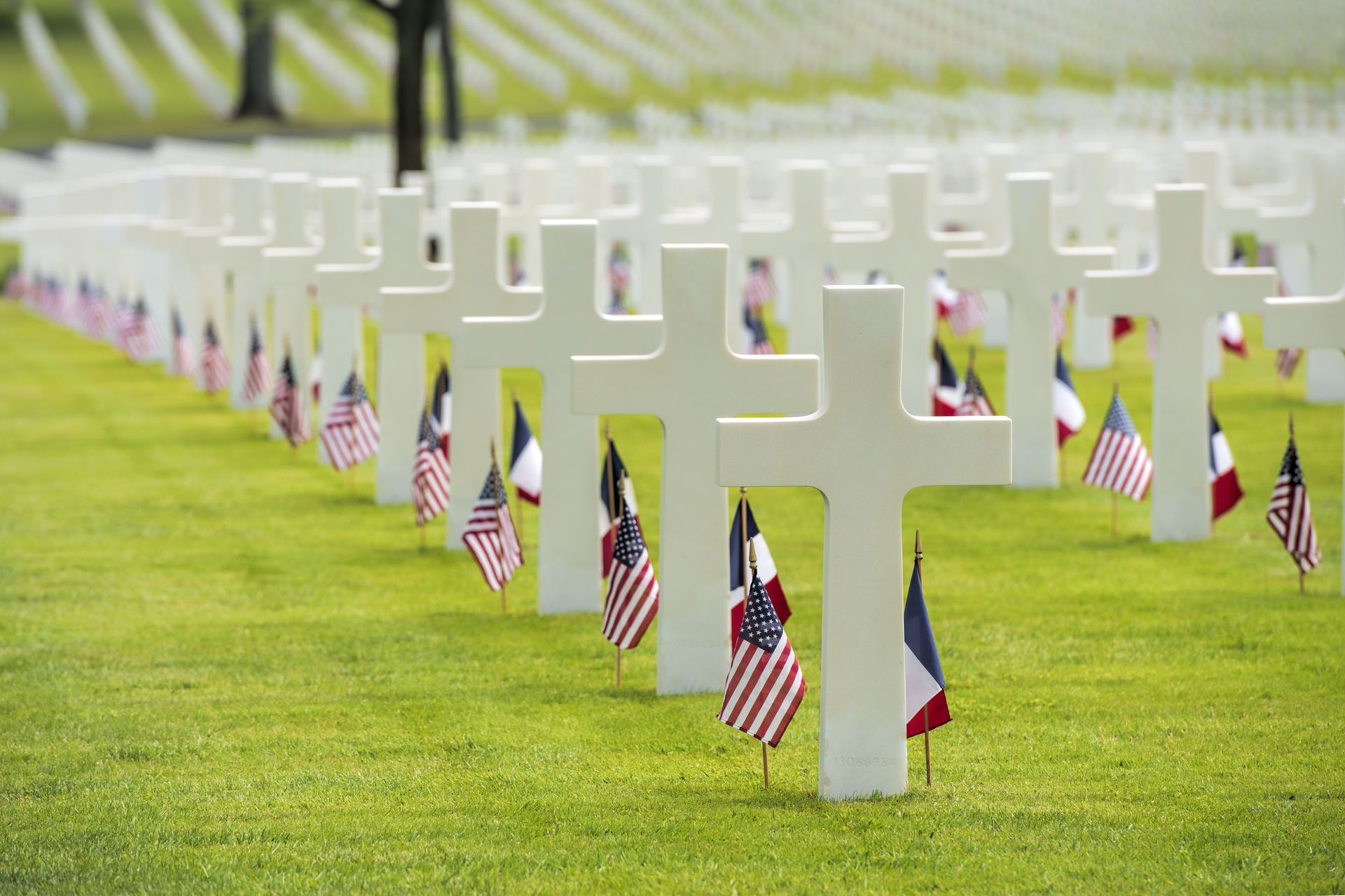 Memorial monuments with white crosses and American flags honoring fallen soldiers in a cemetery.