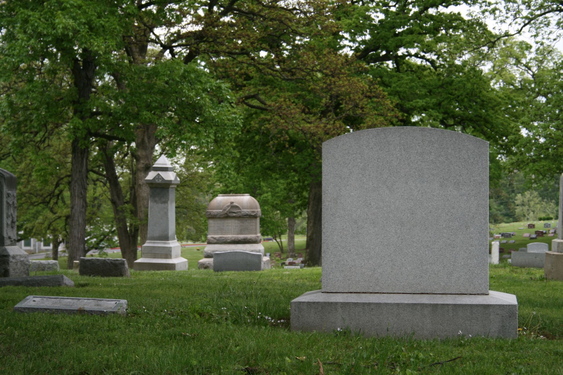 Close-up of a tombstone, showcasing memorial monuments, with cemetery and tombstones behind.
