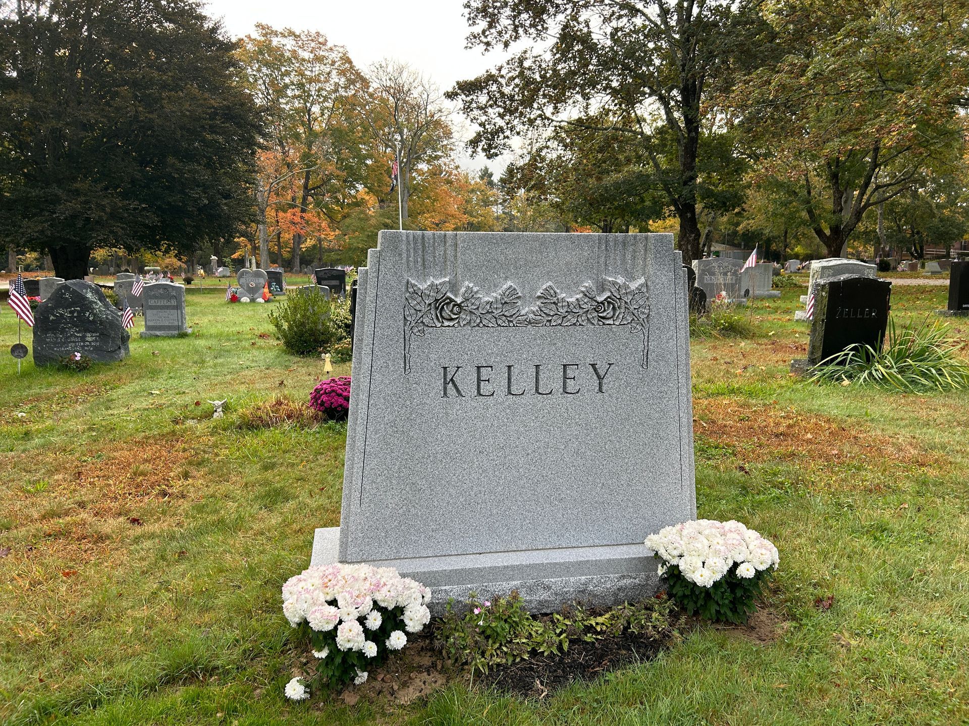 Cemetery with numerous stone tombstones of varying sizes and shapes among trees.