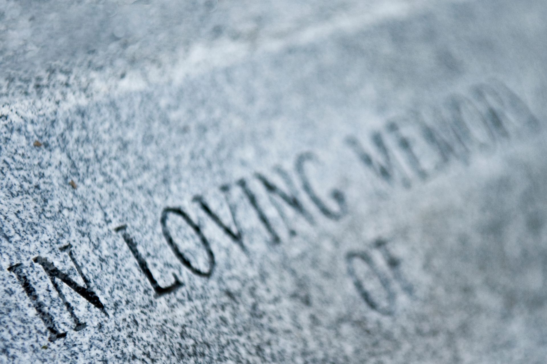 Close-up of a gray granite tombstone with the etched words 