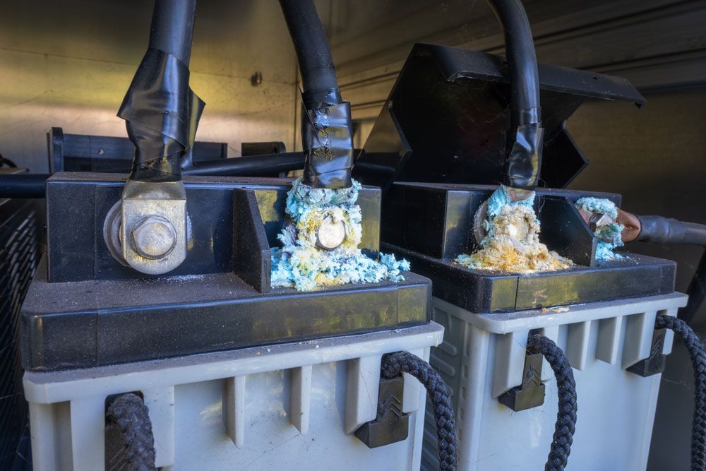 Two batteries with corrosion on terminals and black cables.