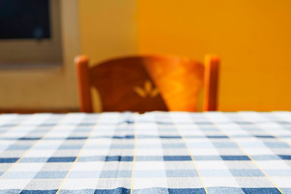 a table with a blue and white checkered tablecloth and a chair in the background .