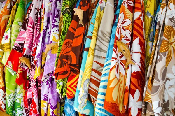 a bunch of colorful hawaiian shirts are hanging on a rack .