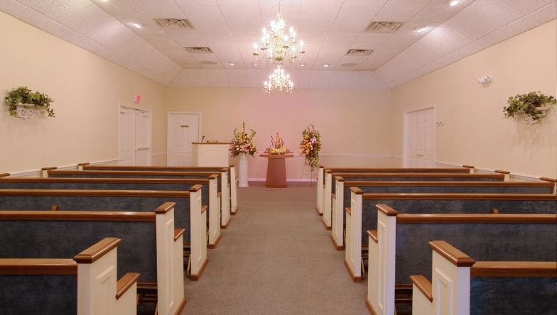 An empty church with rows of benches and a chandelier