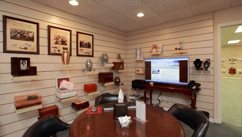 A room with a table and chairs and a television on the wall.