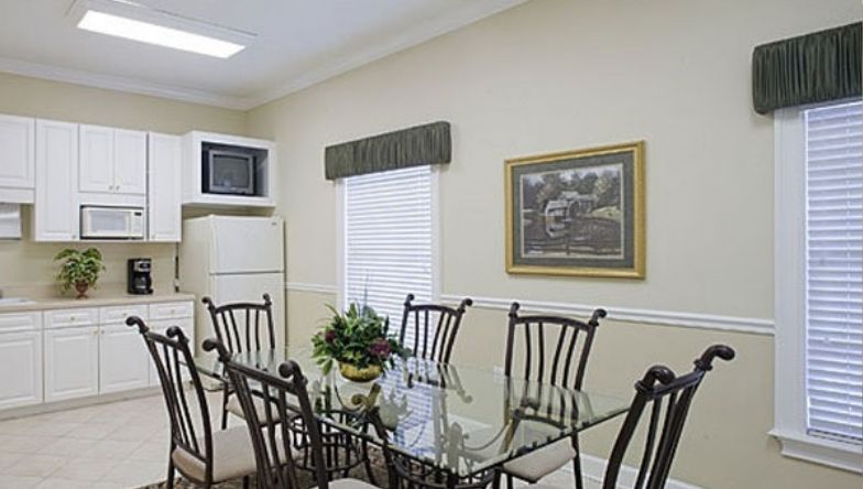 A dining room with a glass table and chairs in a kitchen.