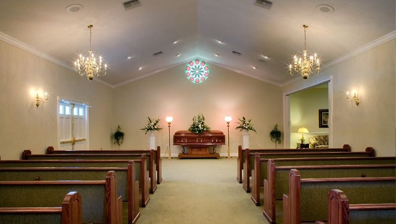 An empty church with rows of benches and a chandelier