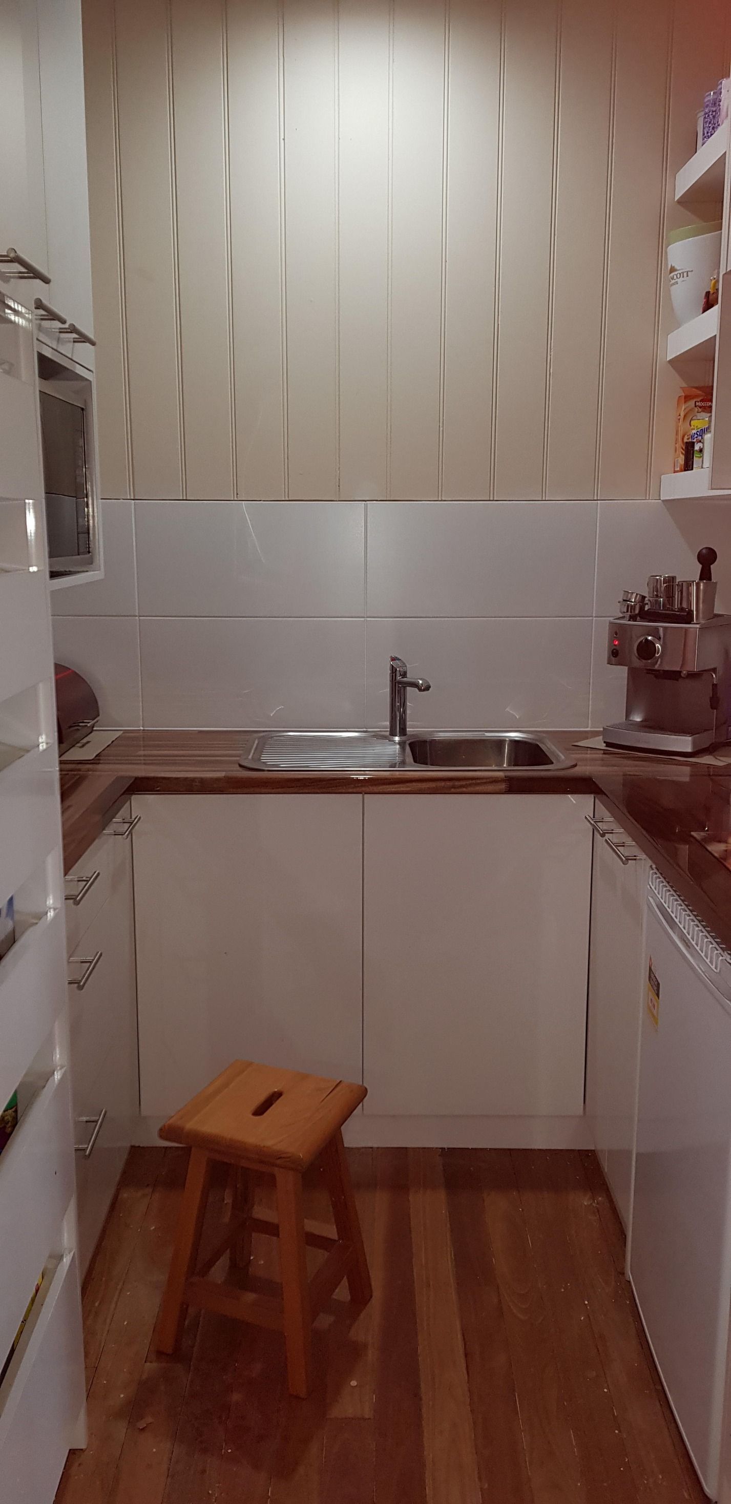 There is a wooden stool in the middle of the kitchen.