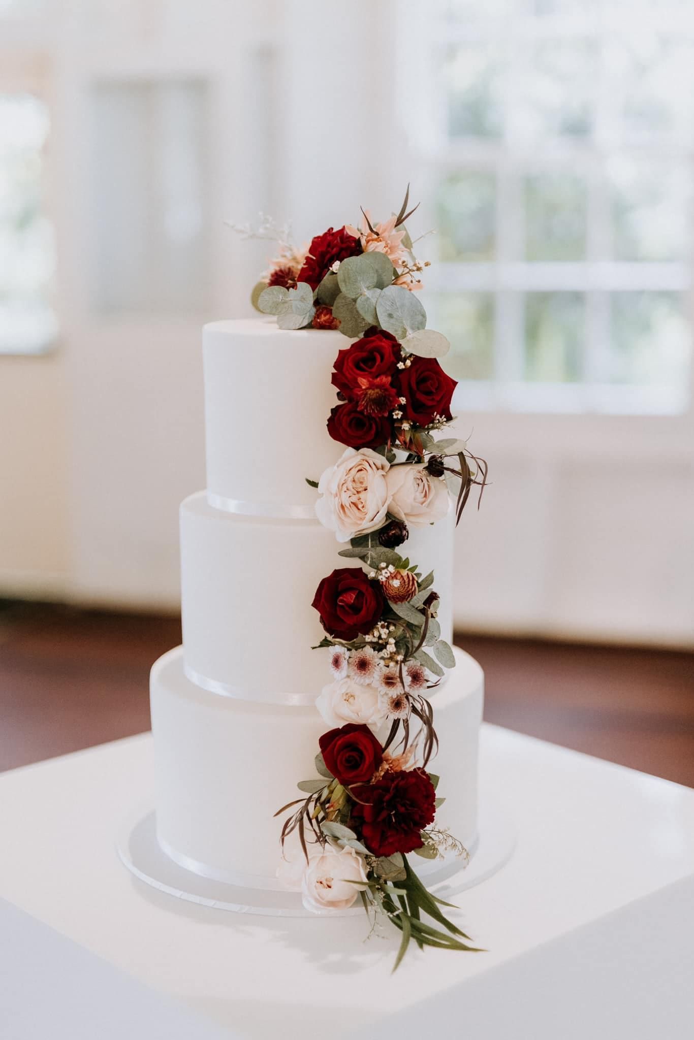 A White Wedding Cake With Red Flowers on It is Sitting on Top of a White Table — Flowers by Suzanne in Morpeth, NSW