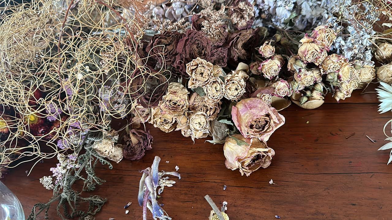 Dried flowers of various types and colors on a wood surface.