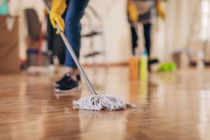 A person is mopping a wooden floor with a mop.