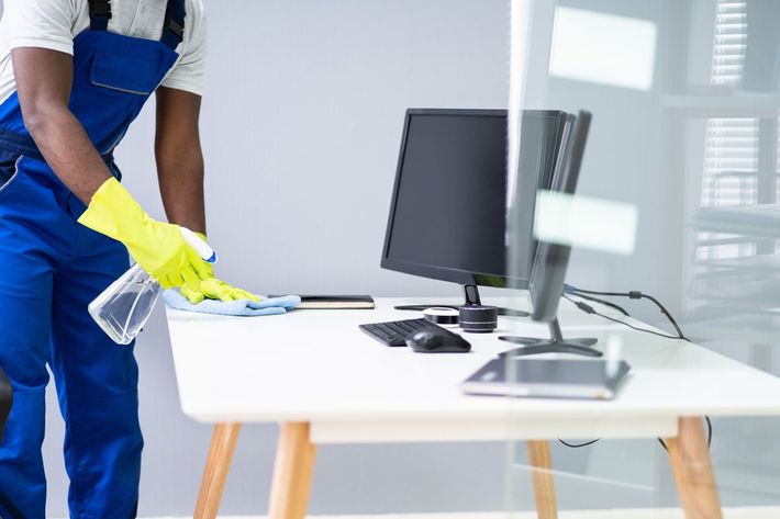 A man is cleaning a desk with a computer on it