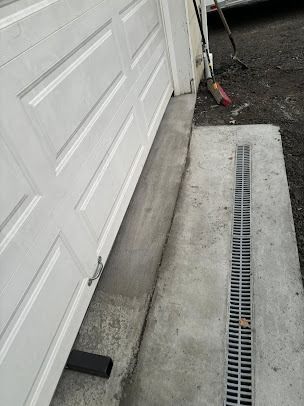 Garage door with concrete ramp leading to a drain.