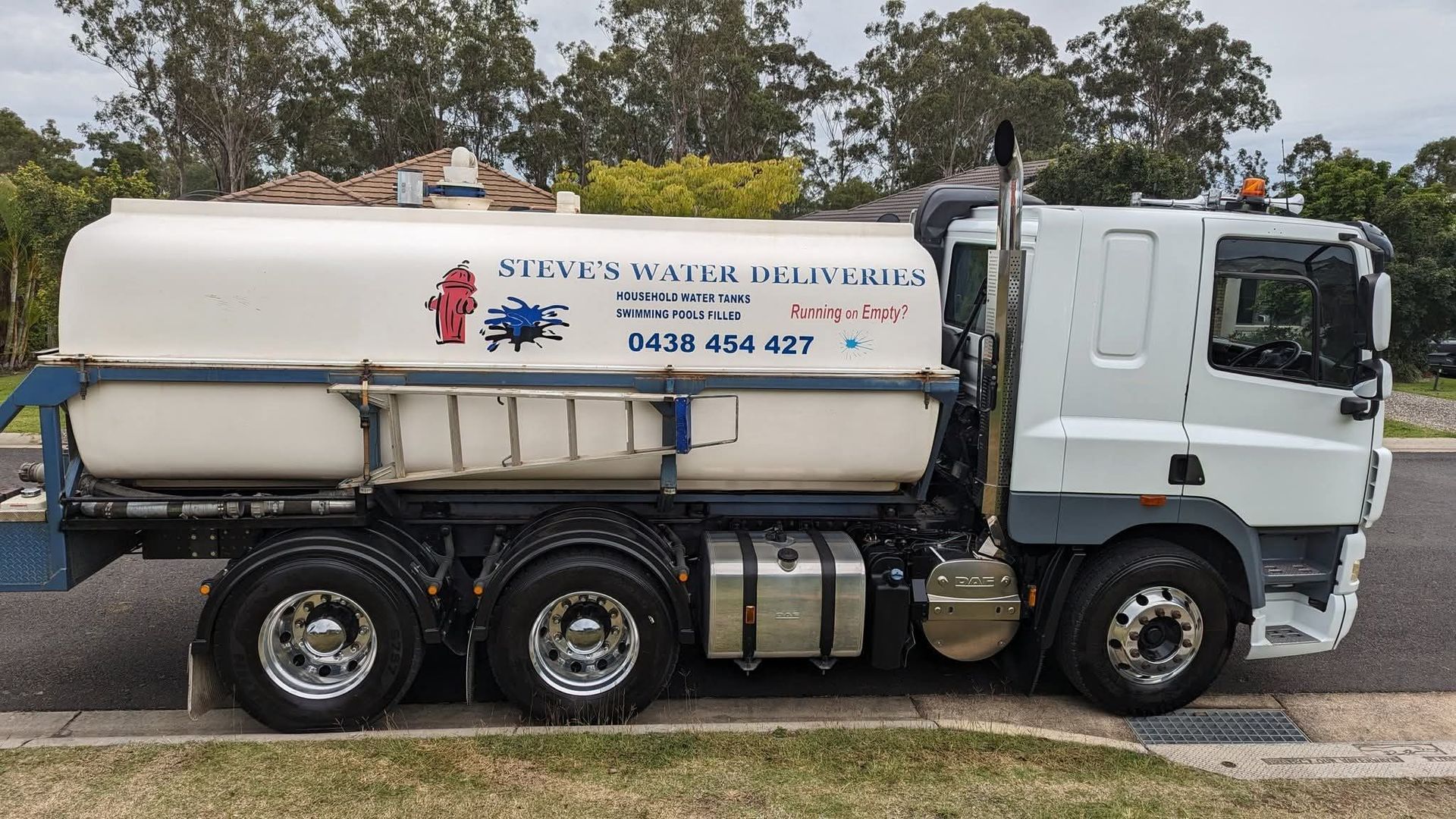 White water delivery tanker truck parked on the side of a suburban street.