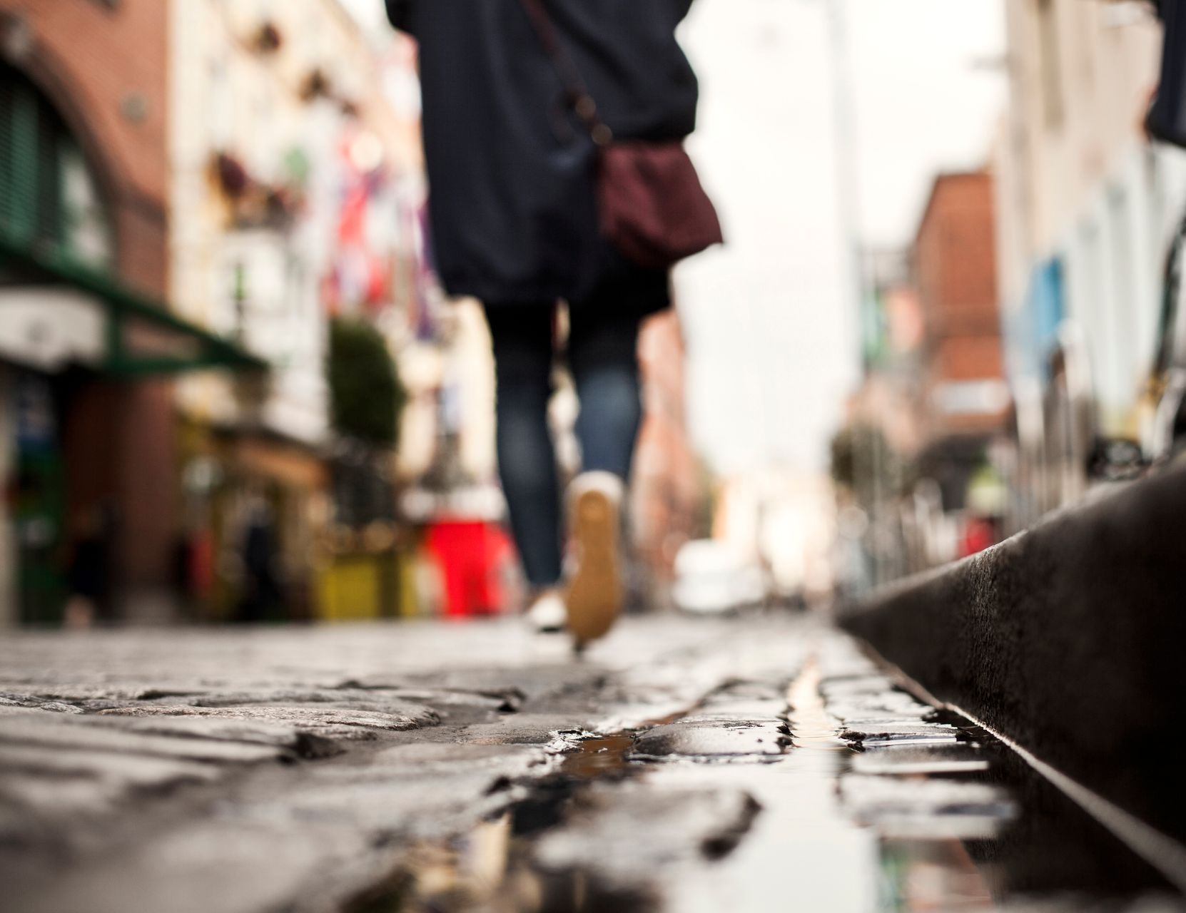 A person is walking down a wet city street.