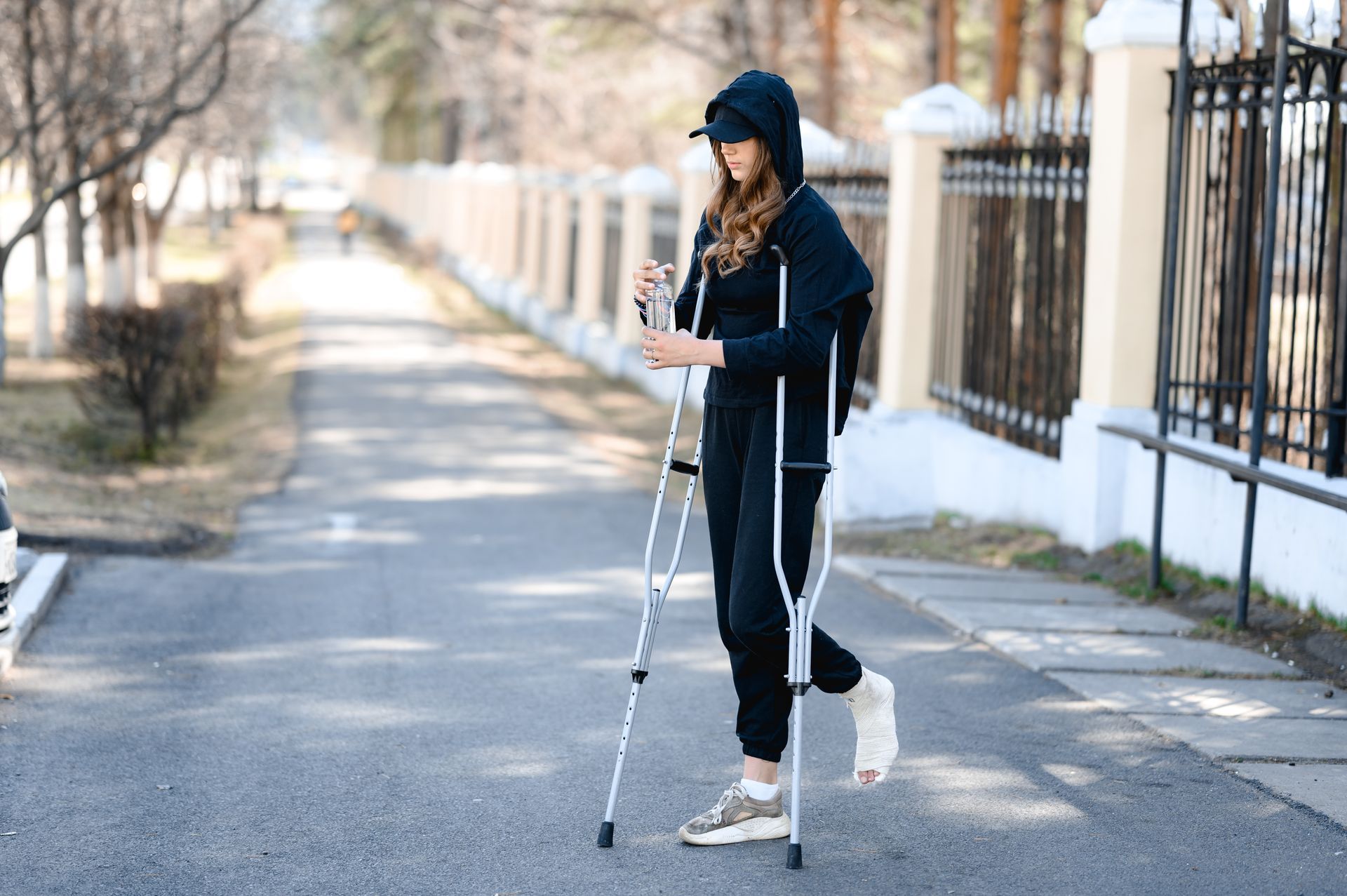 A woman with crutches is walking down the street.