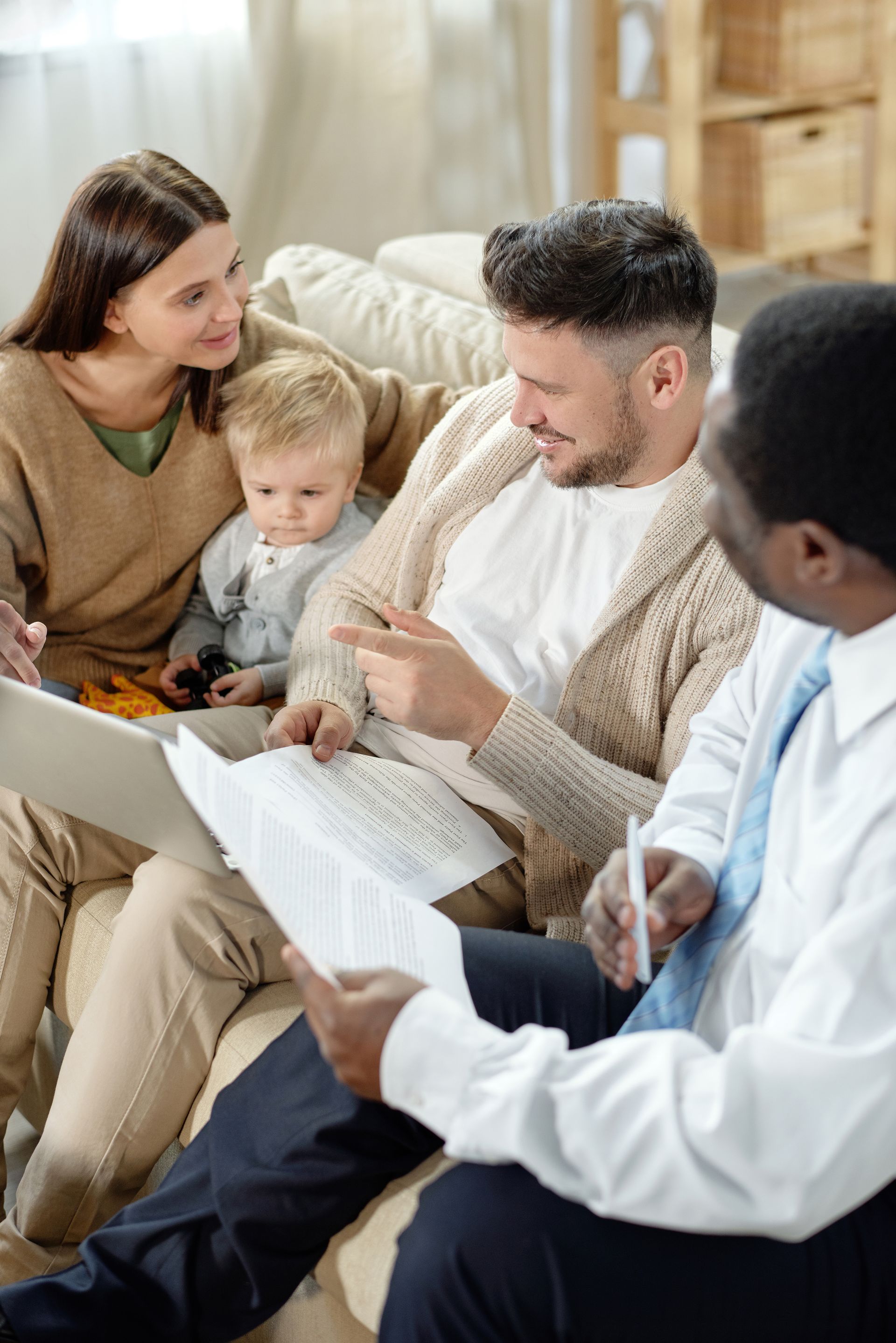 A group of people are sitting on a couch looking at papers.