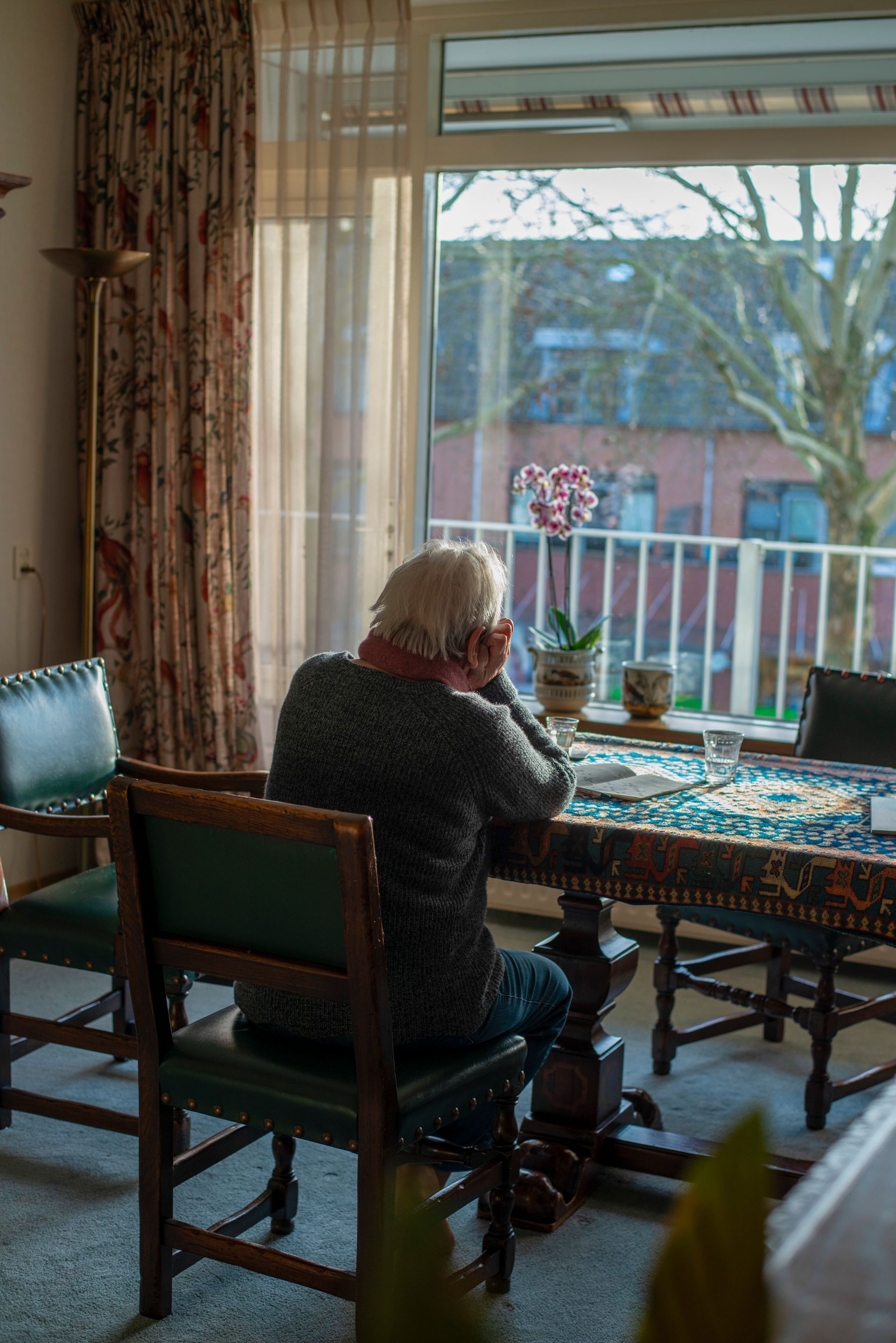 An elderly man is sitting at a table talking on a cell phone.