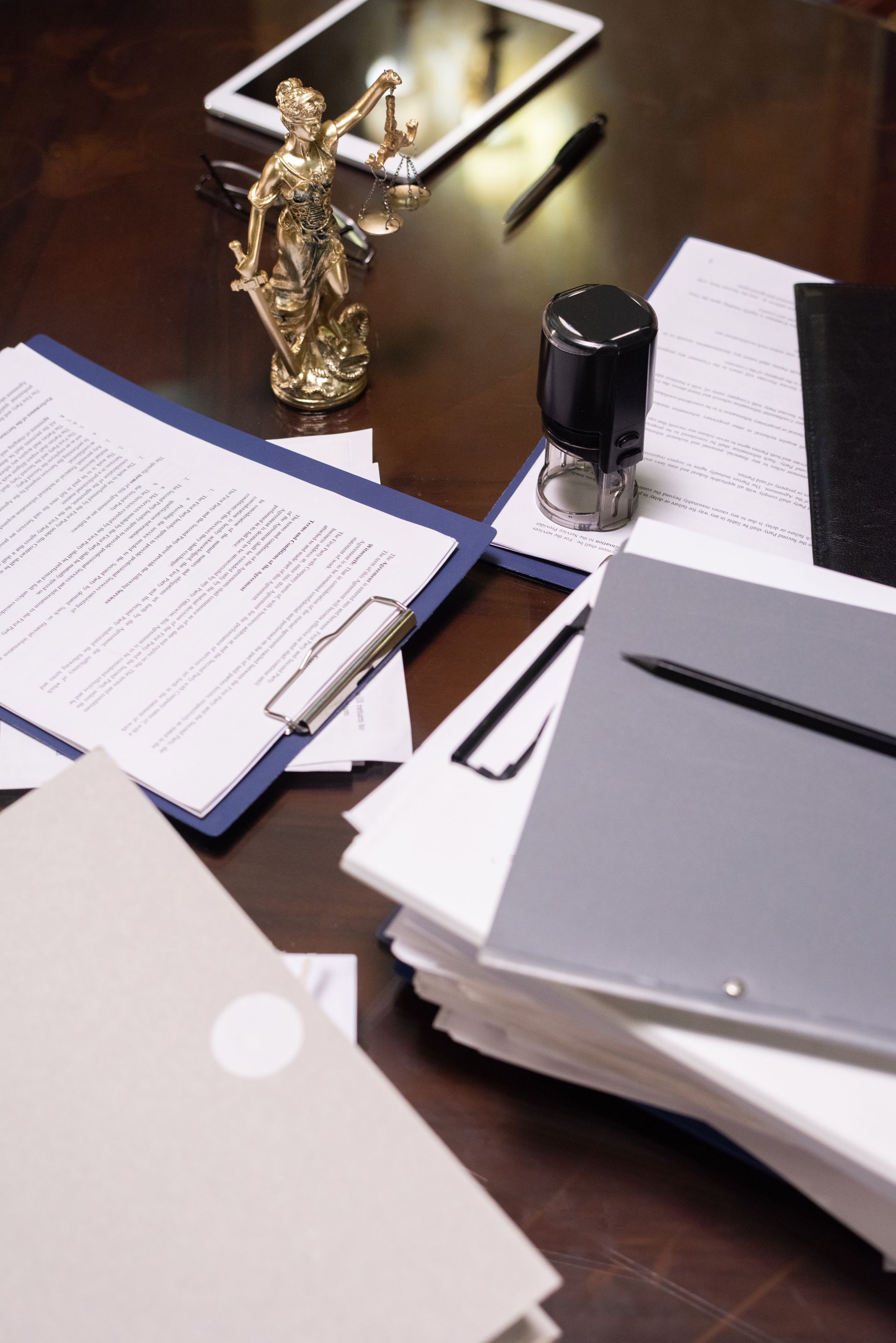 A statue of justice is sitting on a desk next to a stack of papers.