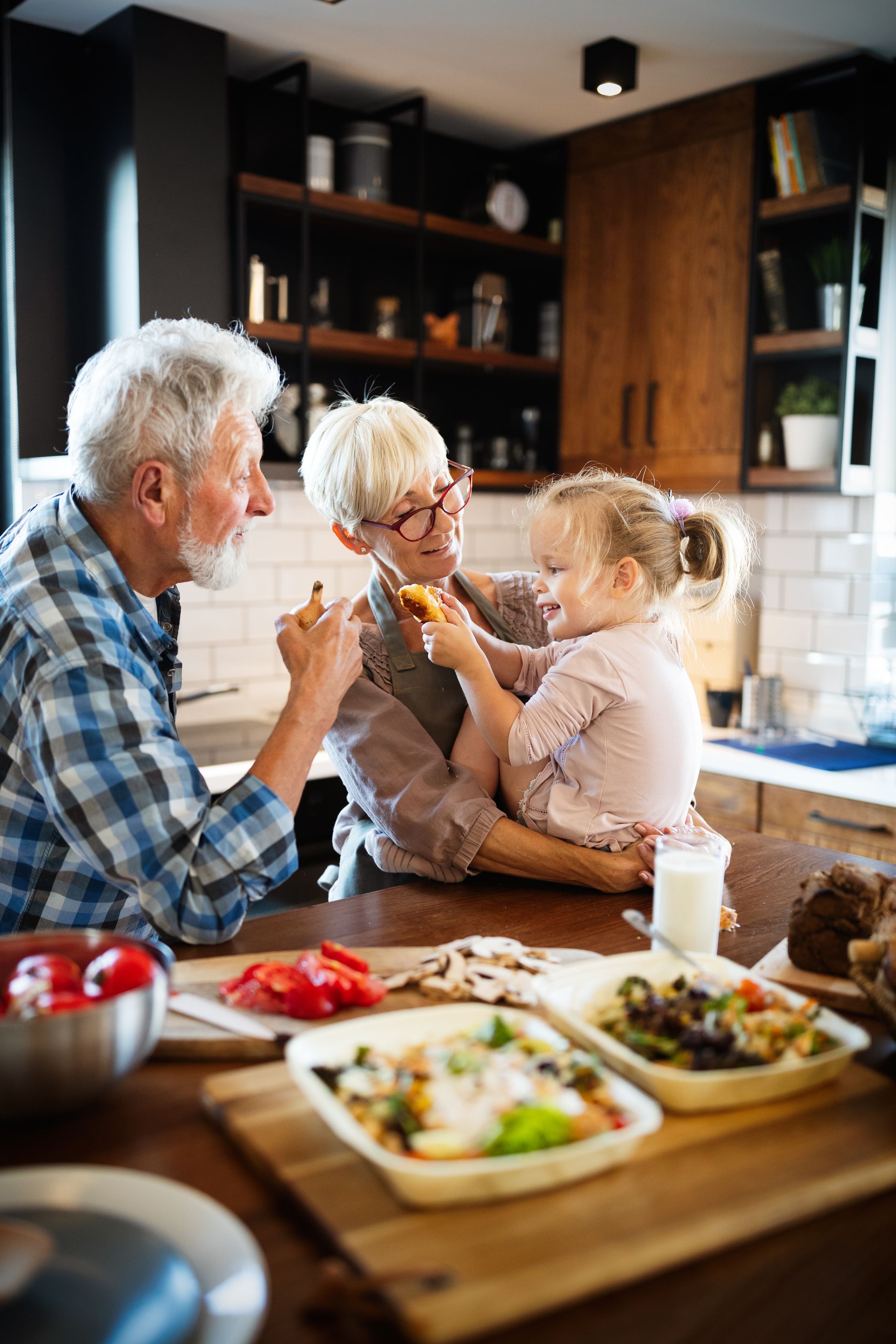 An elderly couple and a little girl are sitting at a table in a kitchen eating food.