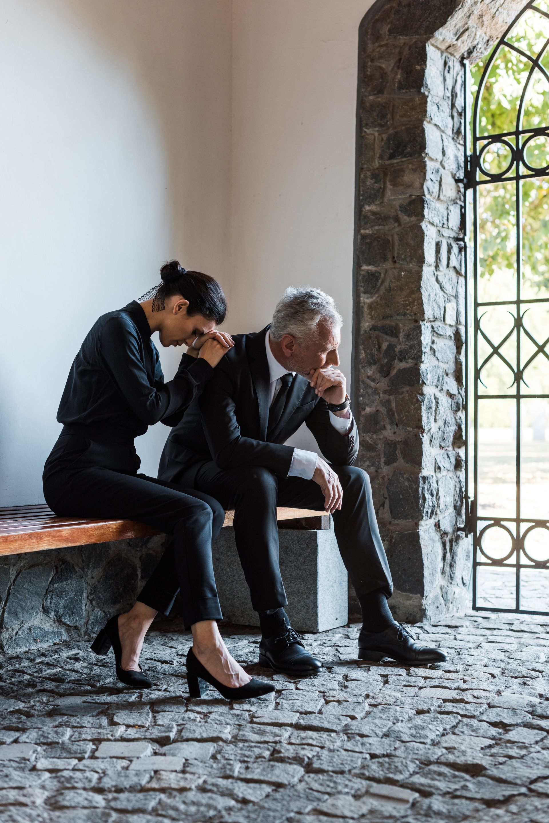 A man and a woman are sitting on a bench at a funeral.