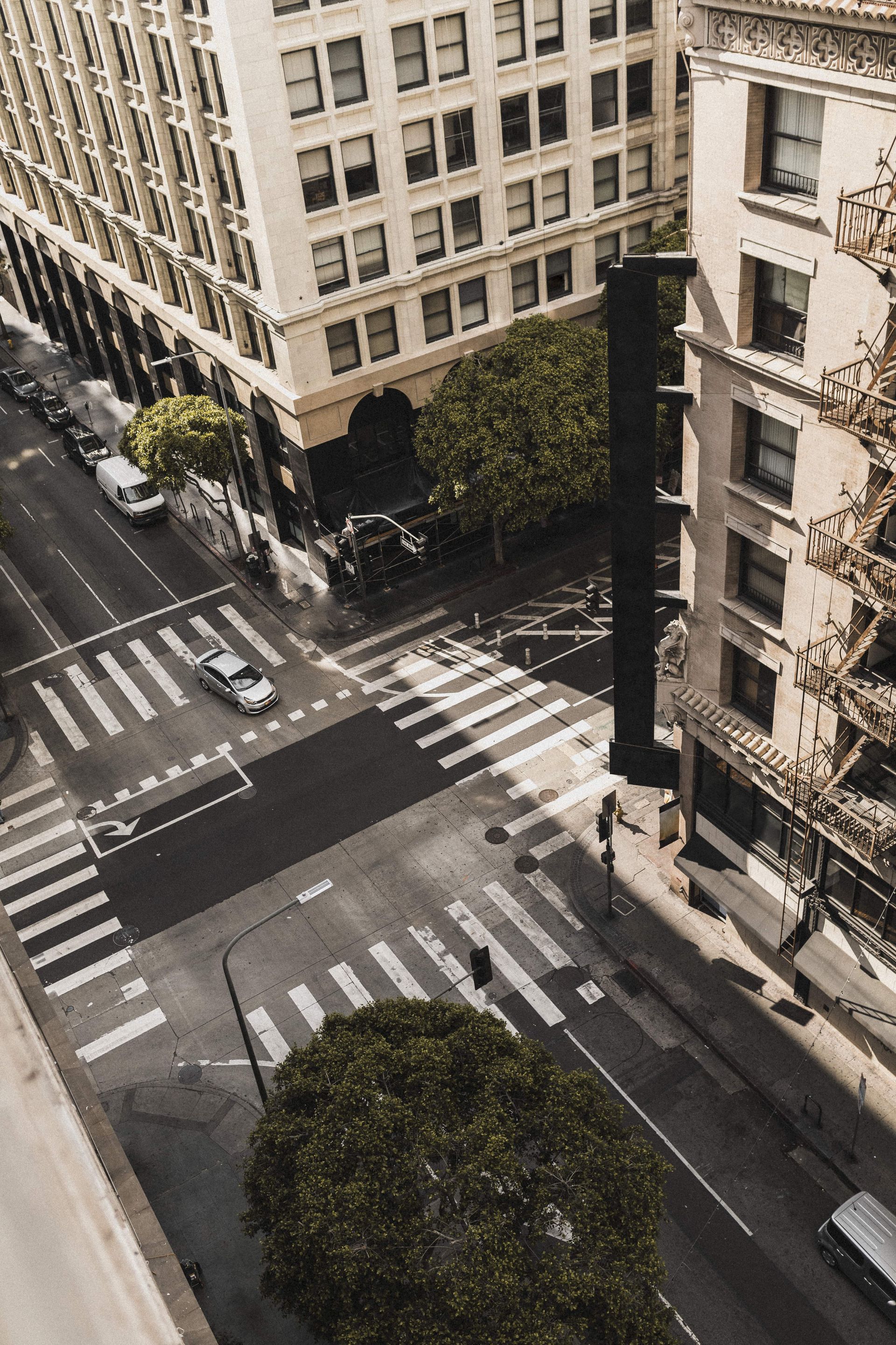 An aerial view of a city street with a crosswalk and a building in the background.