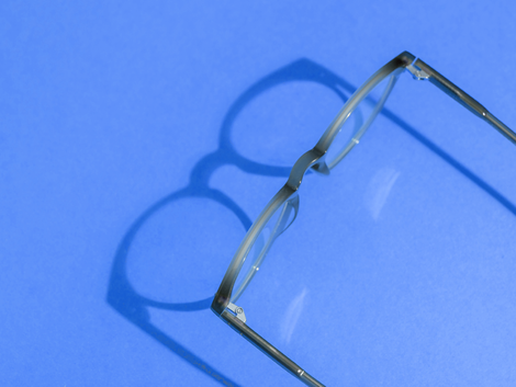 Un paio di occhiali è appoggiato su una superficie blu.