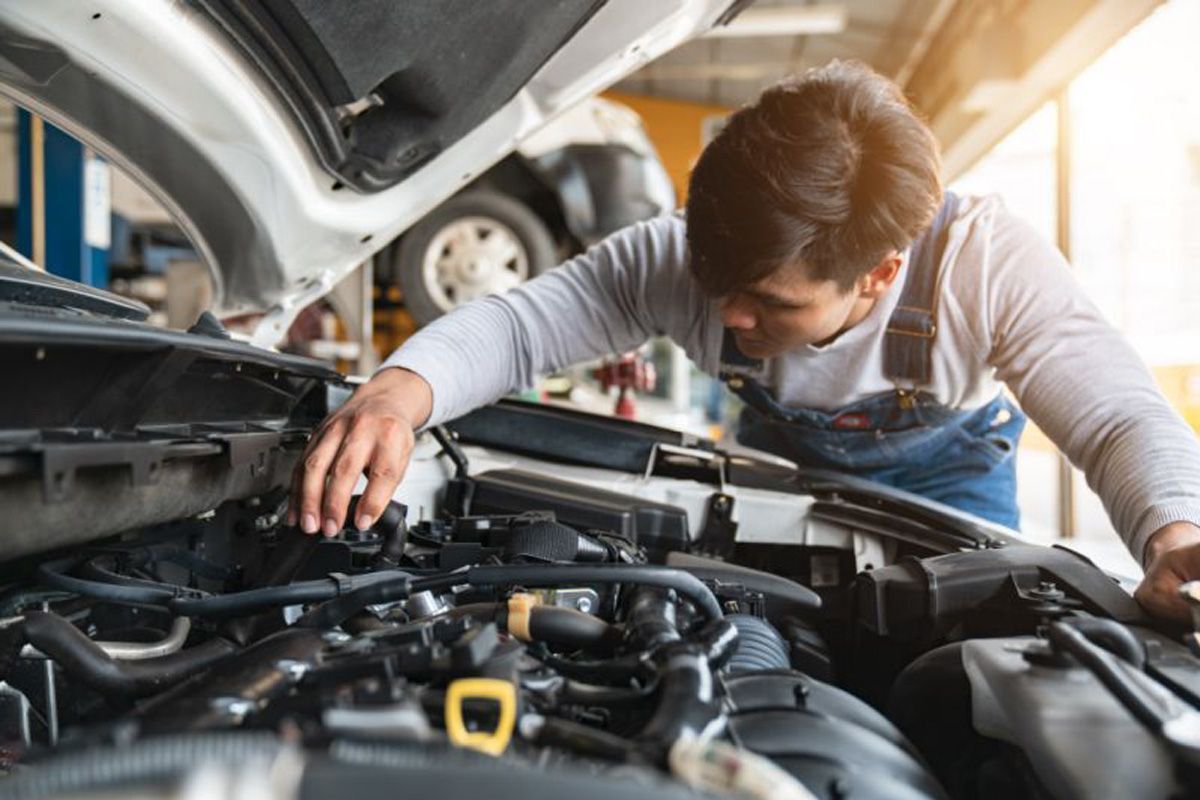 A man is working on the engine of a car in a garage - Walt's Auto & Electric