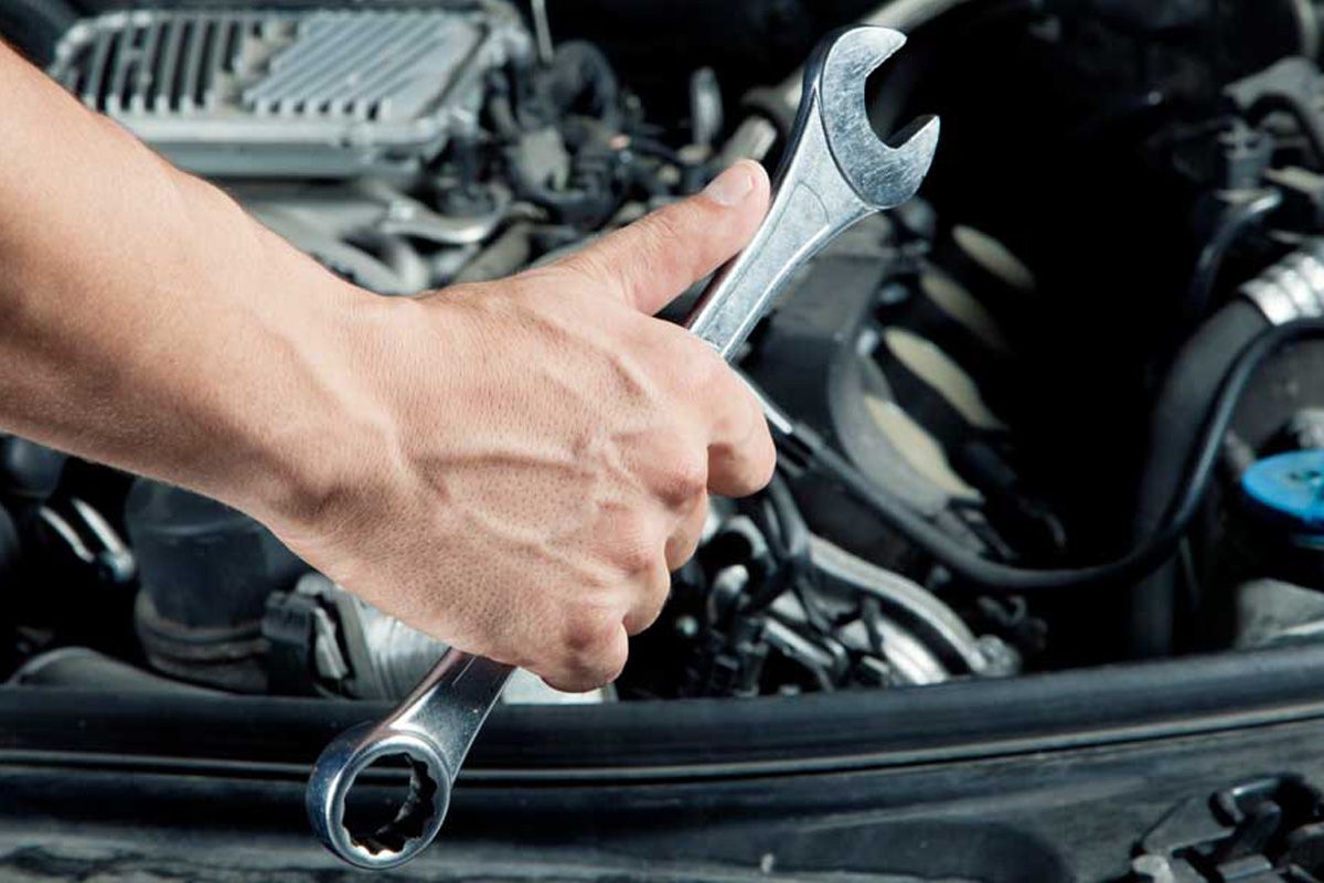 A person is working on a car with a wrench - Walt's Auto & Electric