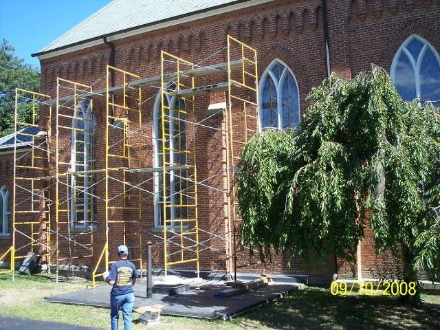 A Man Standing in Front of A Brick Building with Scaffolding on It | Detroit, MI | Yellow Rose Builders