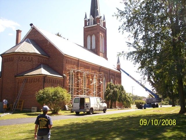 A Man Stands in Front of A Large Brick Building with A Van Parked in Front of It on 9/10/2008 | Detroit, MI | Yellow Rose Builders