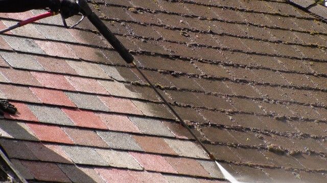 A Person Is Cleaning a Roof with A High Pressure Washer | Detroit, MI | Yellow Rose Builders