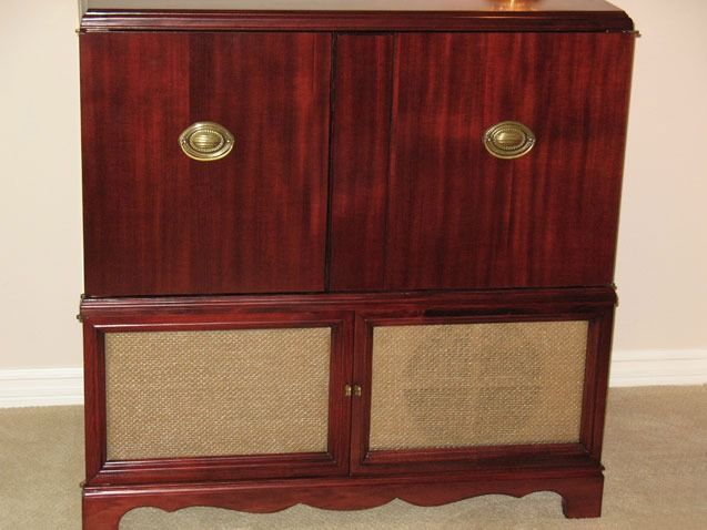 Dark wood cabinet with woven front panels and round brass handles against a beige wall.