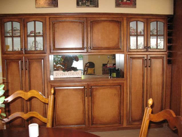 Wooden kitchen cabinet with glass-front doors and a central mirror above a counter