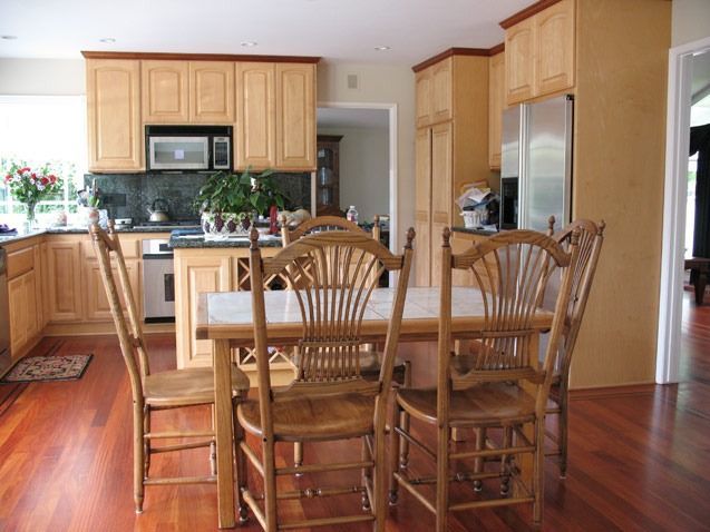 Bright kitchen with wooden cabinets, island, and dining table on hardwood floors