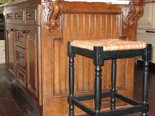 Wooden kitchen island with a black padded stool in front of it