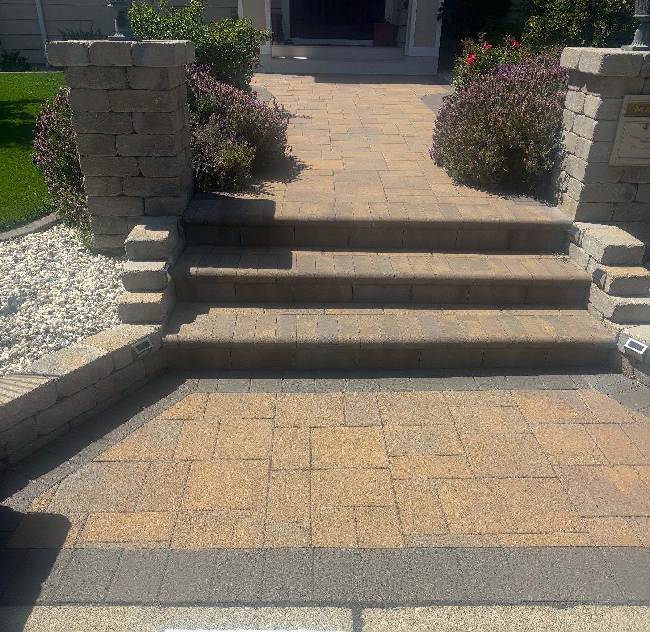 Brick steps leading up to a house entrance with bushes on either side.