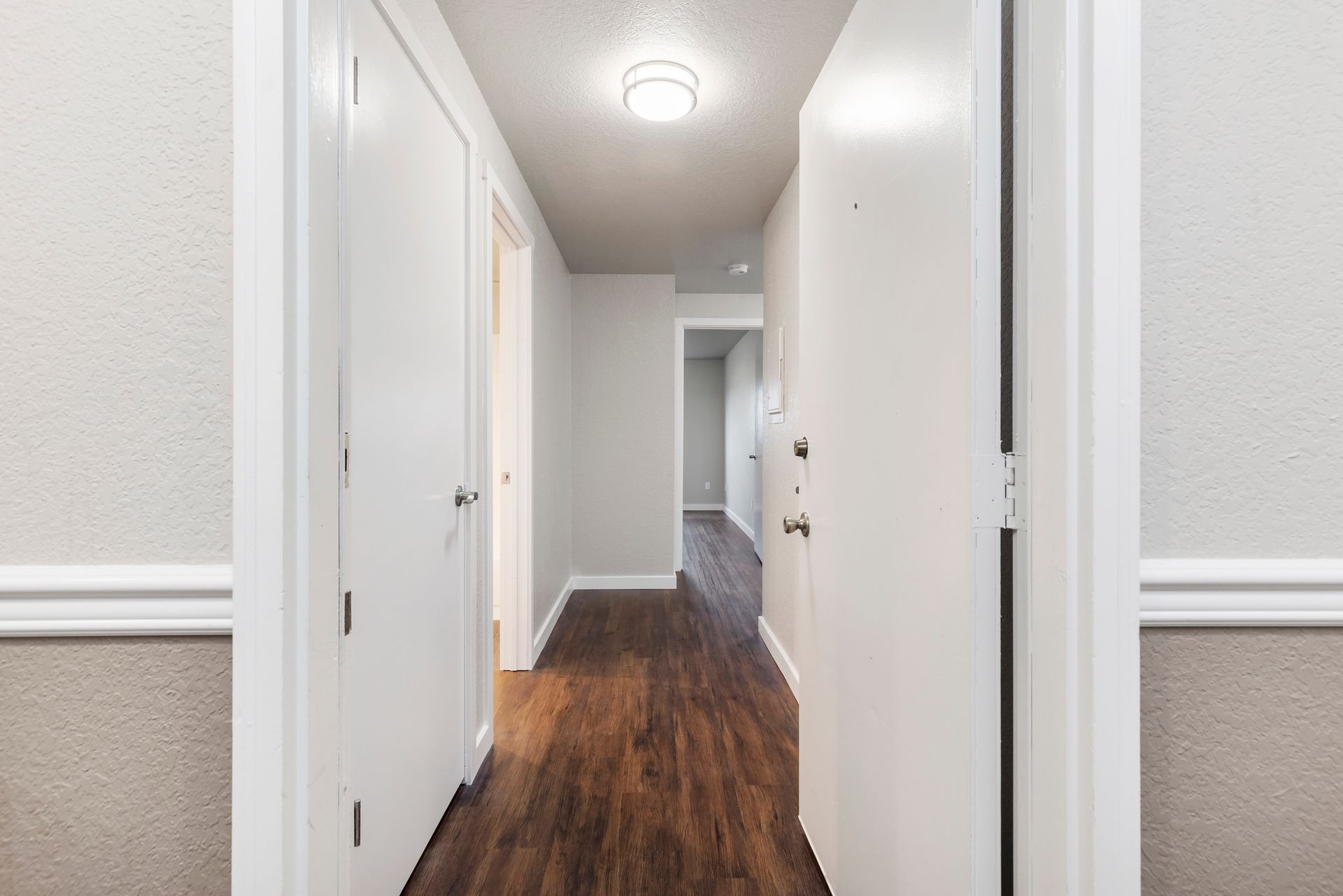 a hallway with wooden floors and white doors in a house .