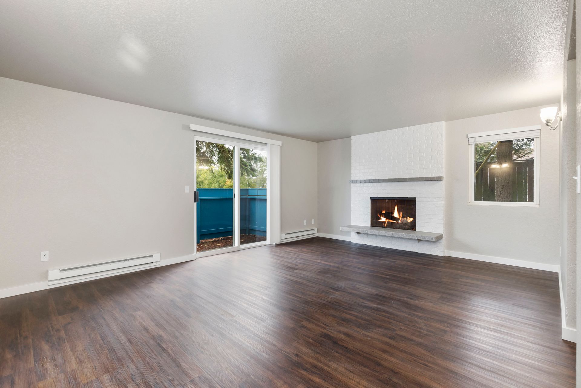an empty living room with hardwood floors and a fireplace .