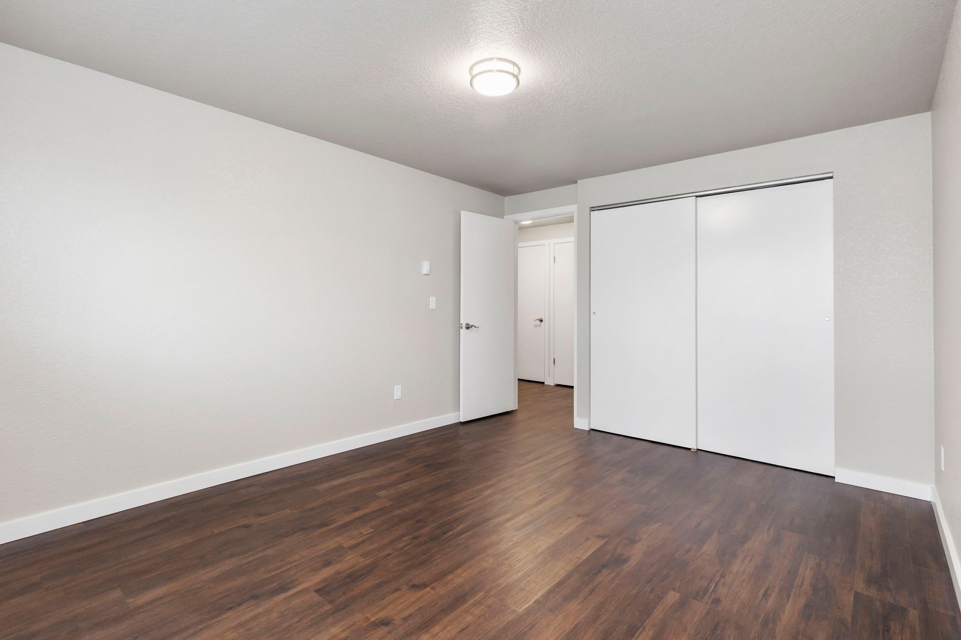 an empty bedroom with hardwood floors and white walls .