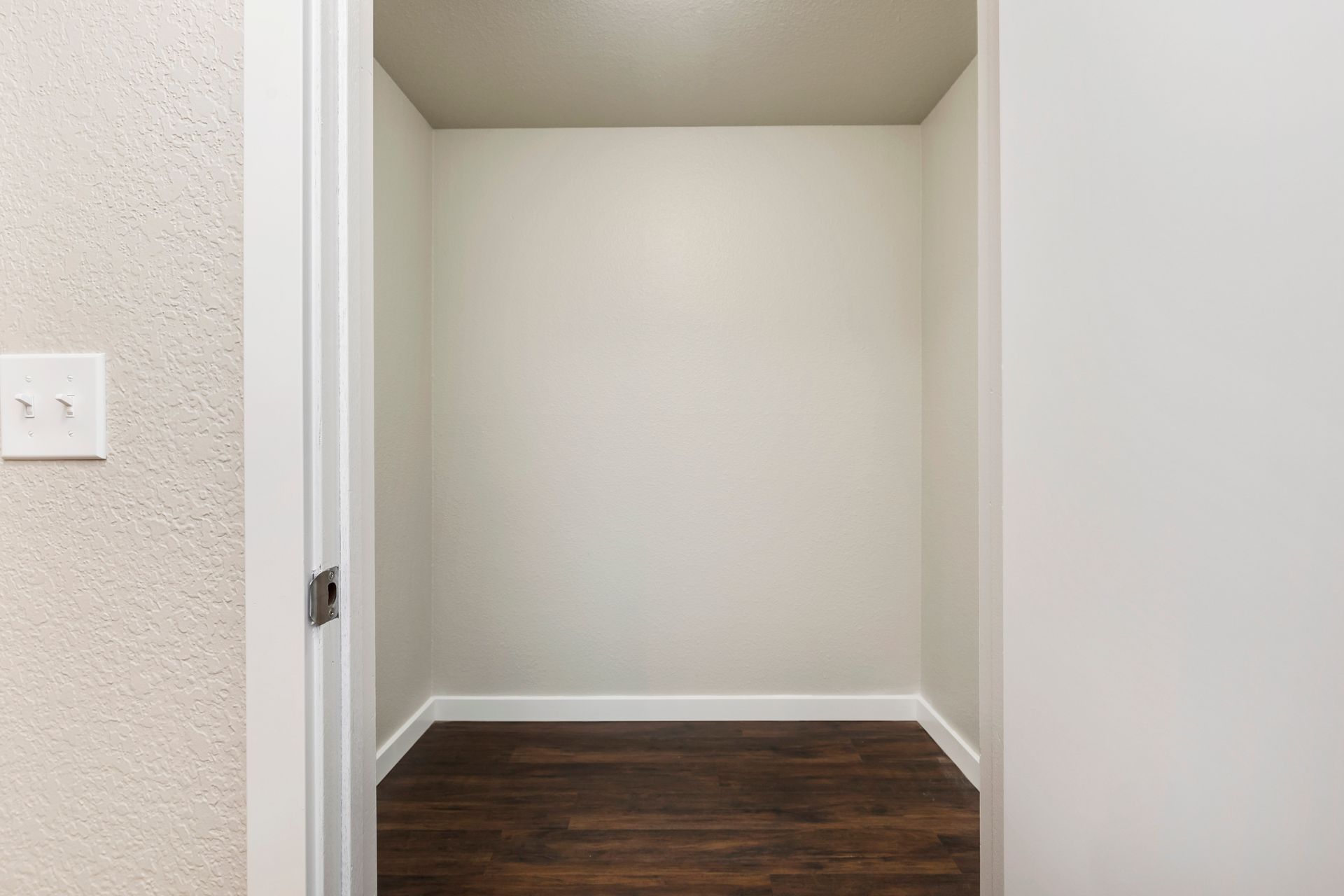 an empty closet with a wooden floor and white walls .
