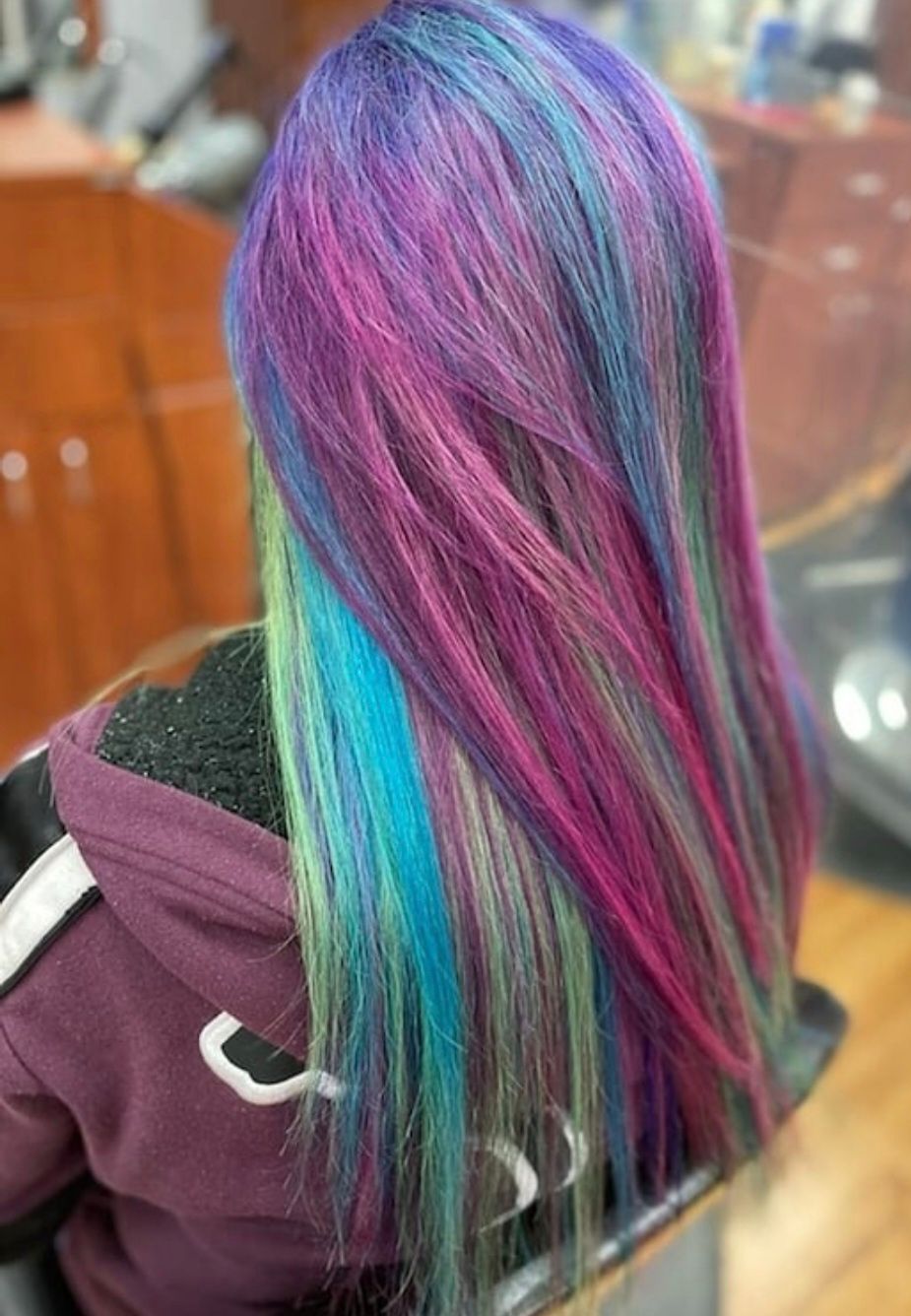 Woman with long hair dyed vibrant blue, purple, teal, green, and pink.