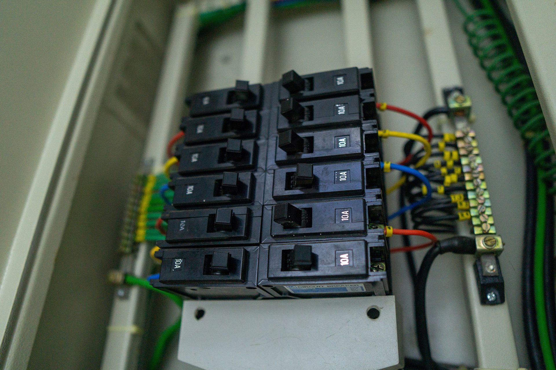 A close-up view of an open electrical breaker panel with multiple switches and colorful wiring connections.
